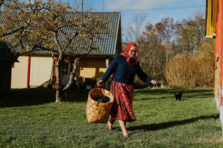 一个穿着传统裙子的女人穿过一片长满草的后院
